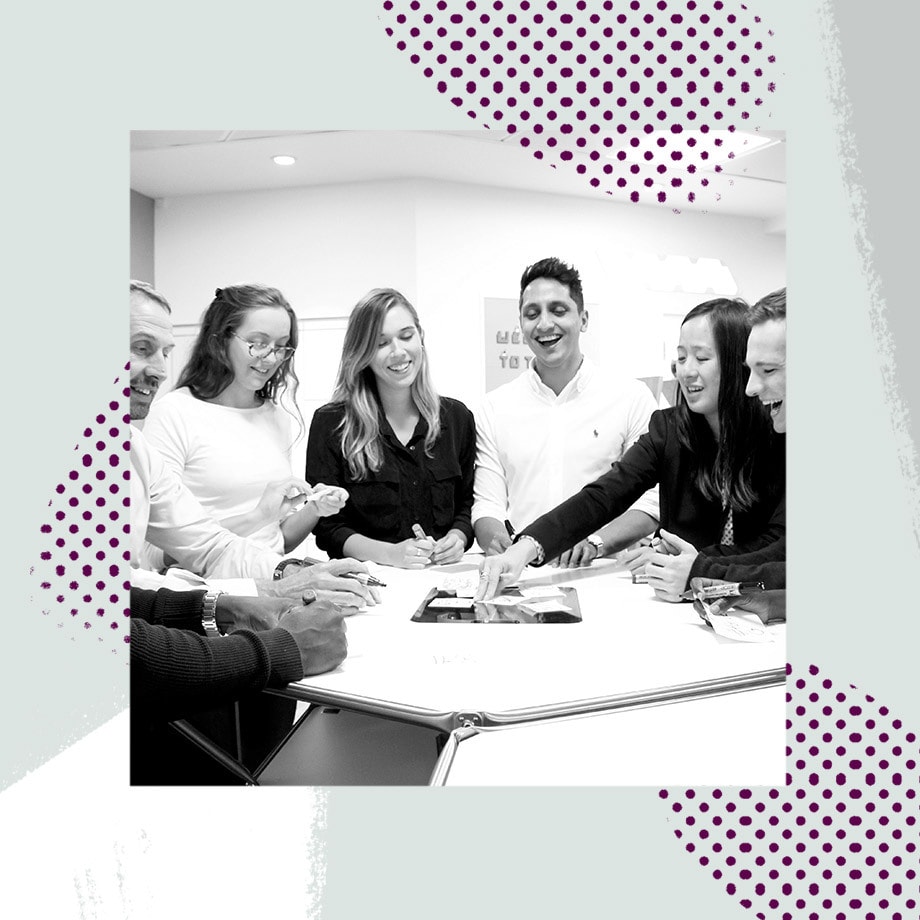 Group of new hires laughing and working around a table